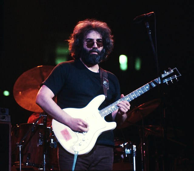 Jerry Garcia playing a cream-colored electric guitar.