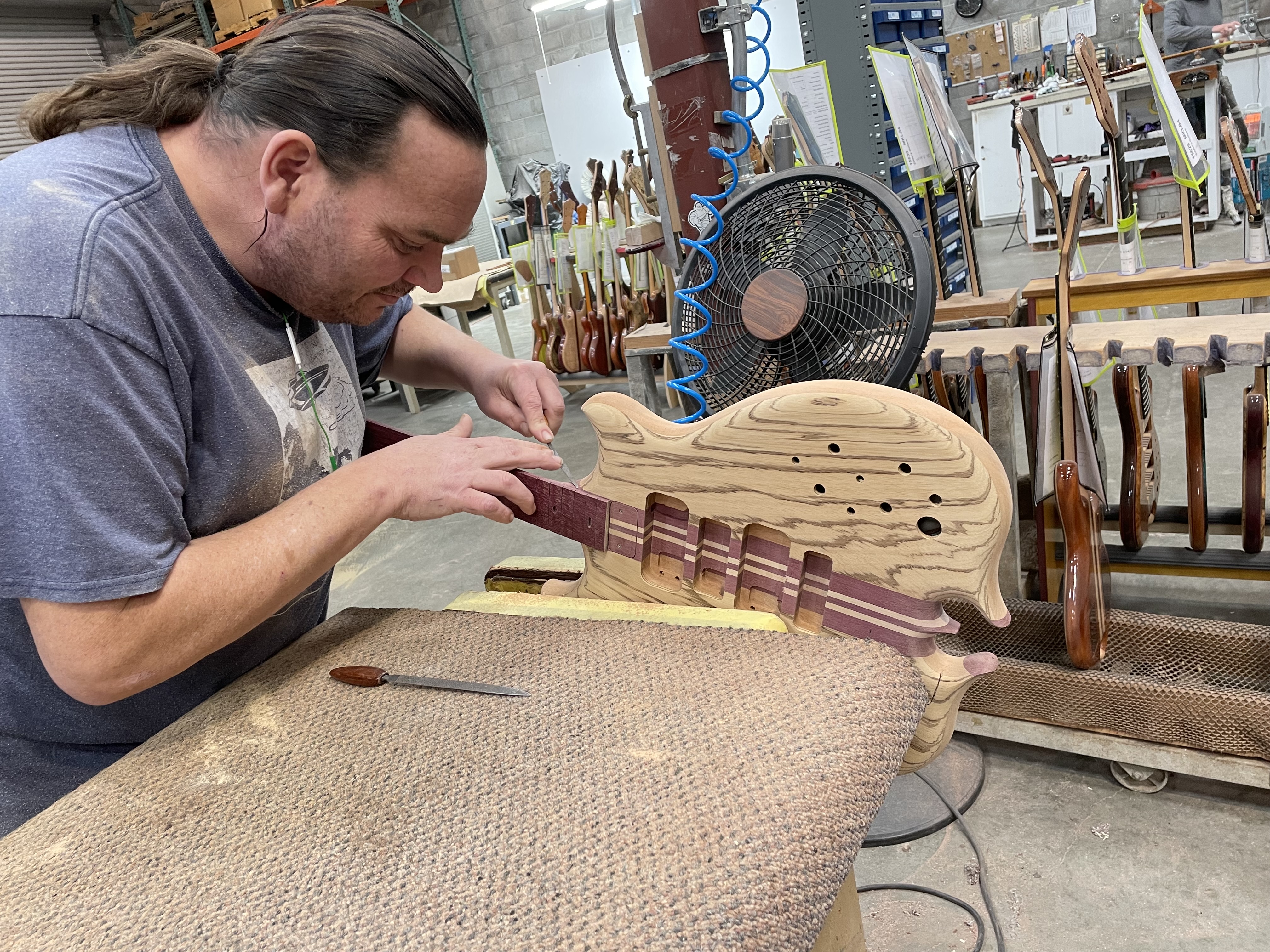 Alembic Luthier performing a detail carving on a Series II custom bass in zebrawood with a purpleheart and maple neck.